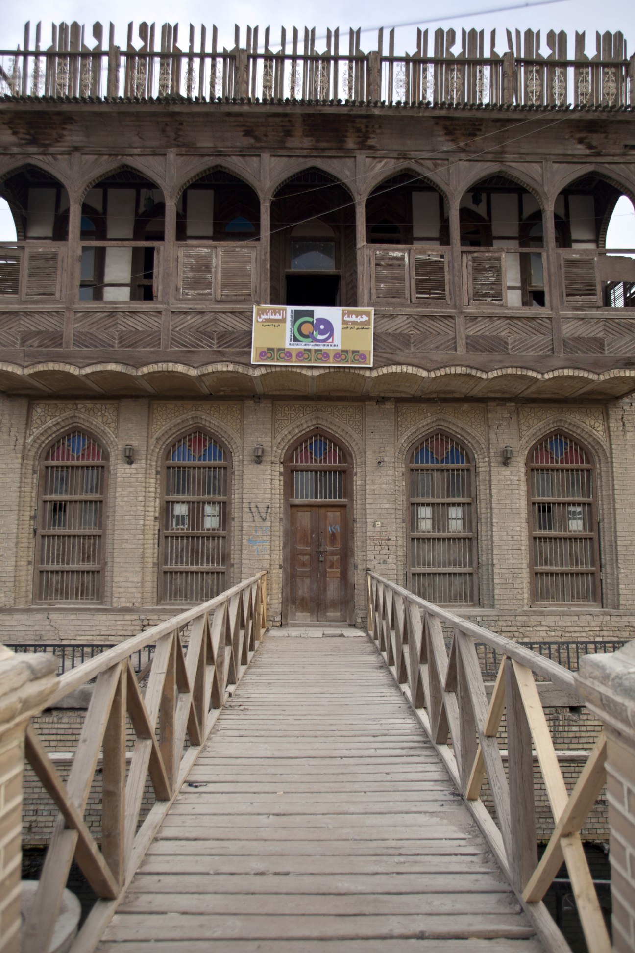 Traditional wooden shanasheel architecture with ornate latticed windows and balcony in historic Basra.