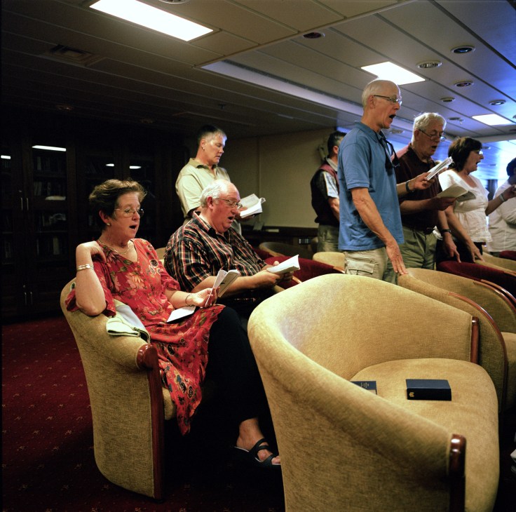 Passengers singing during a Sunday morning church service in the main lounge of the RMS St Helena.