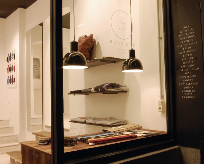 Harvest boutique window display in Munich featuring curated clothing and accessories on shelves under pendant lighting.