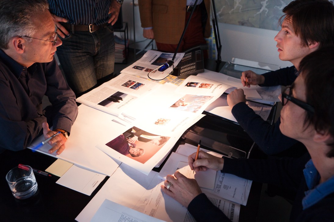 Der Spiegel editorial staff review magazine cover options and layouts during a meeting.