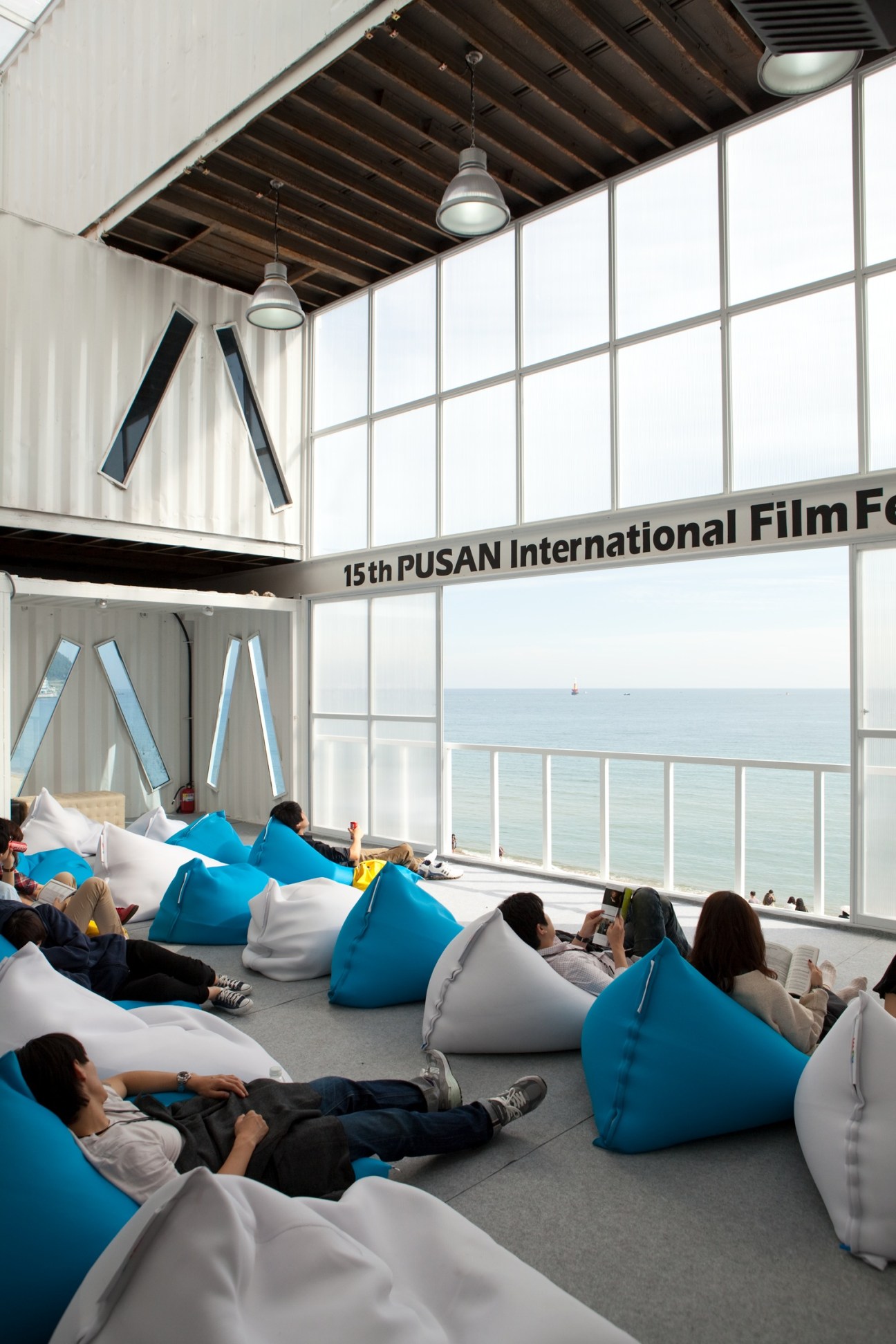 Festival attendees relax on blue and white bean bags in the PIFF pavilion with ocean views.