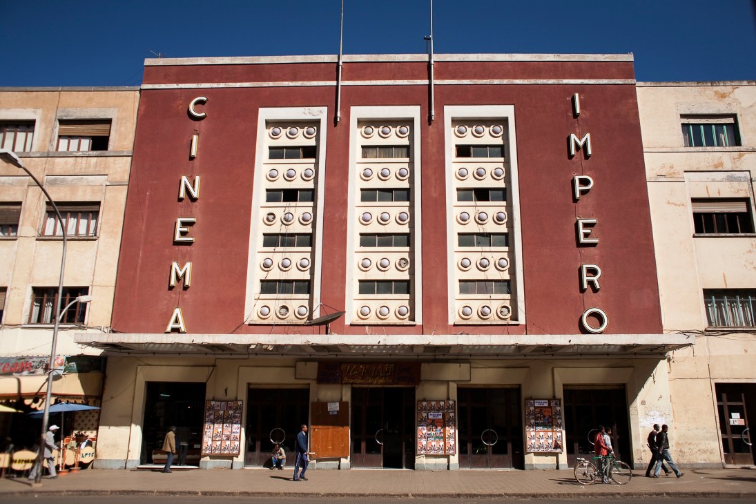 Art Deco cinema with red and cream facade and decorative circular window details in Asmara, Eritrea.