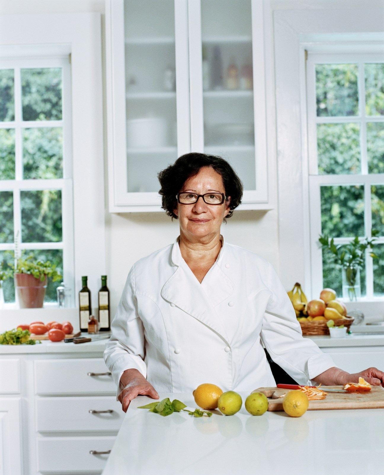 Sonia Salcedo, chef to the Chilean ambassador, stands in a bright kitchen with fresh produce and Chilean wine bottles.