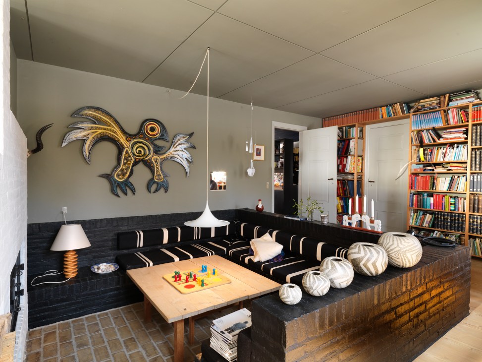 A mid-century modern living room with hanging Flensted Mobiles, black and white striped sofa, and bookshelves.
