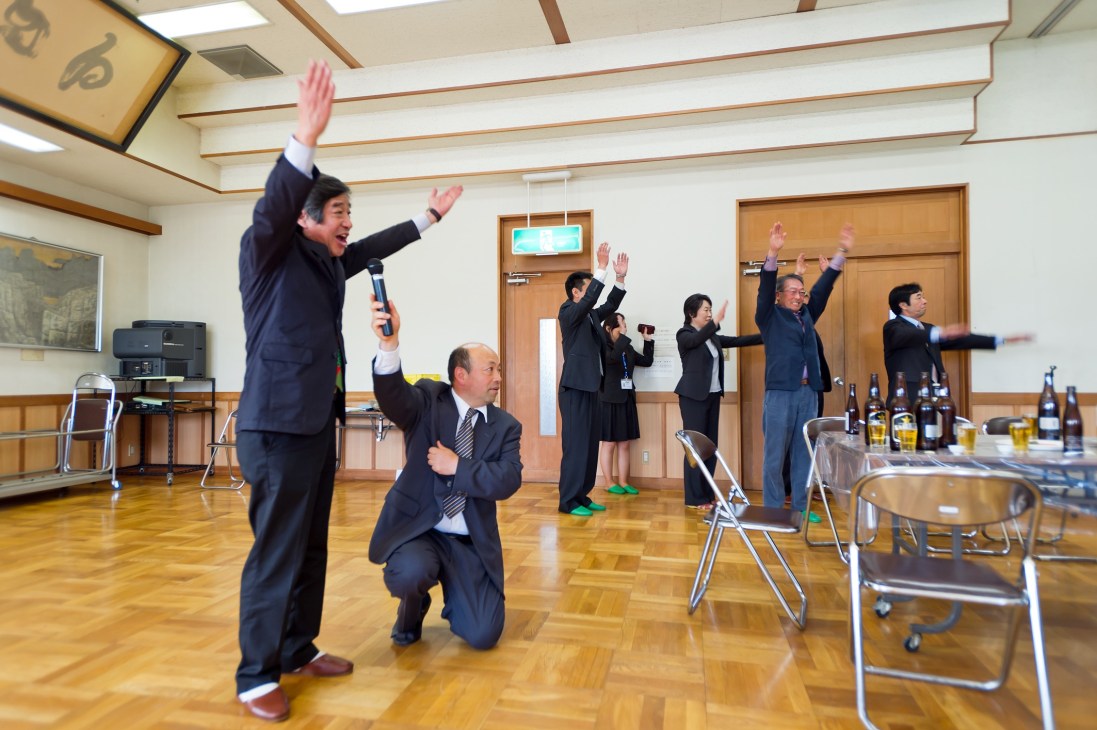 Mayor Ryozo Ichimura leads a group exercise session with officials in a wooden-floored meeting hall in Obuse.