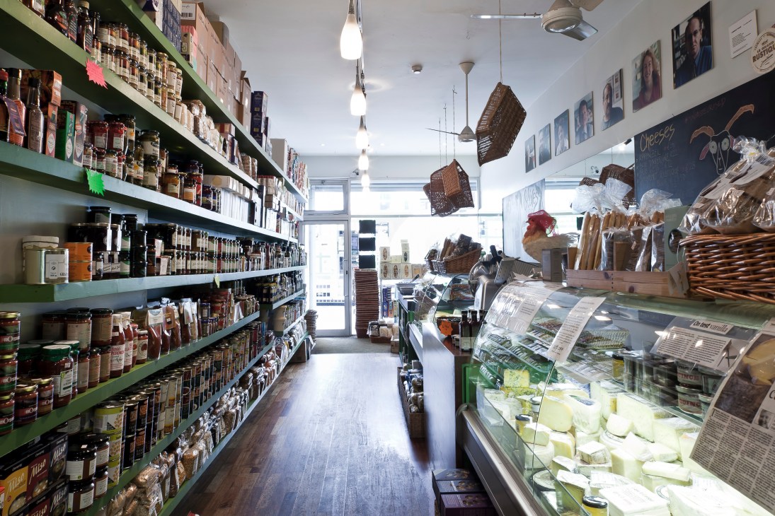 Interior of Listons Food shop with green shelving stocked with packaged products and fresh items in refrigerated display.