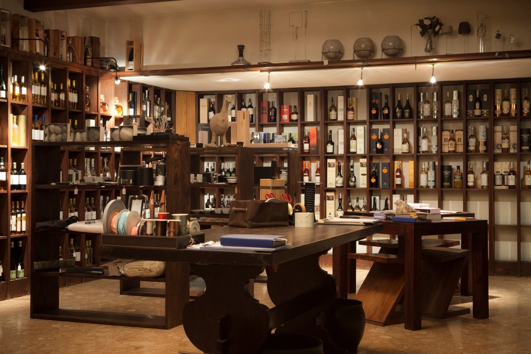 Interior of Casa del Barolo wine shop with wooden shelving displaying bottles and a central tasting table.