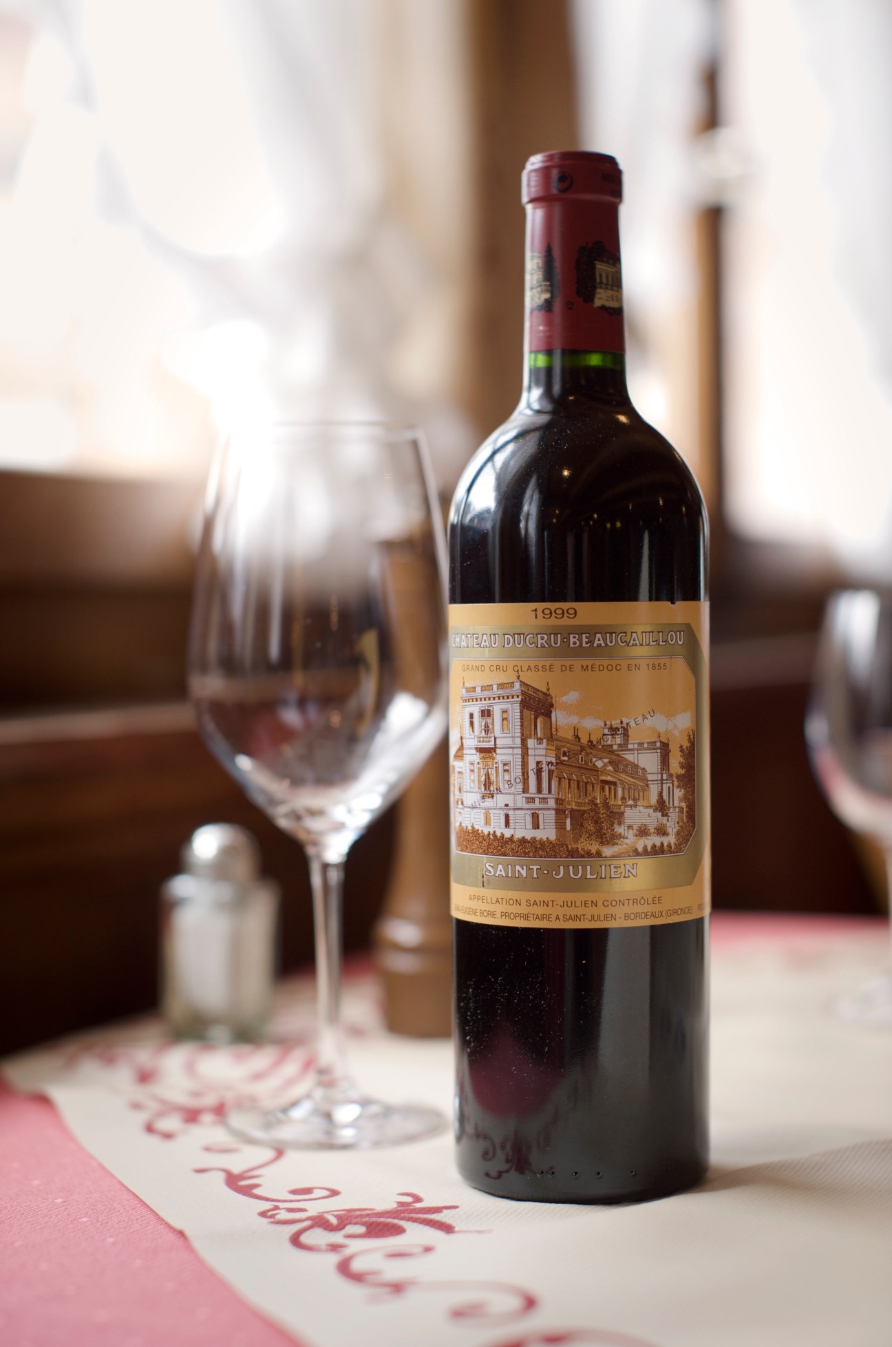 Bottle of Château Ducru-Beaucaillou 1999 Saint-Julien wine with a glass on a restaurant table.