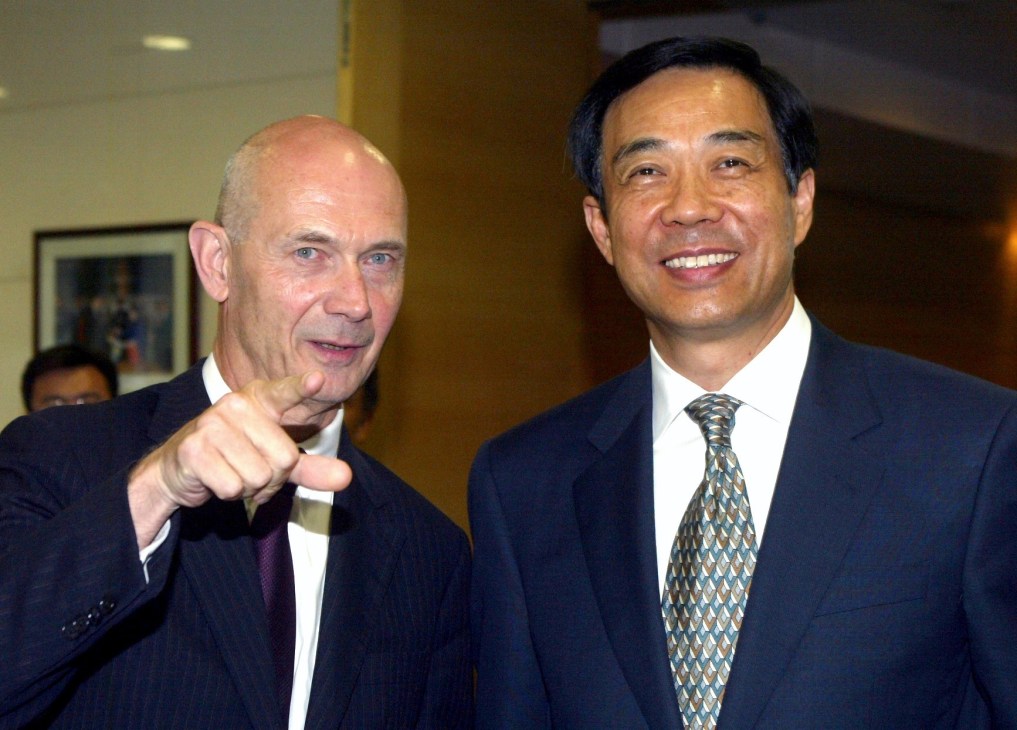 Dalian's mayor Bo Xilai smiles while speaking with a Western businessman in formal attire.