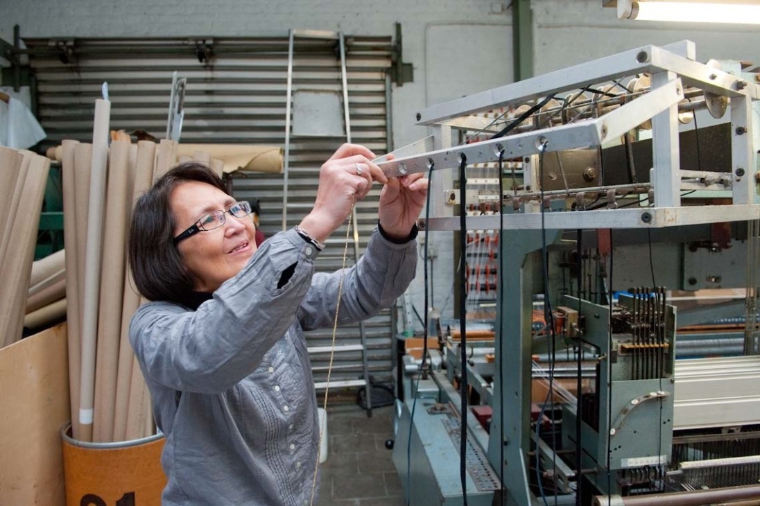 Mrs Sophirat, floor manager at Atelier Charles Schambourg, adjusts a punch card on a weaving loom.