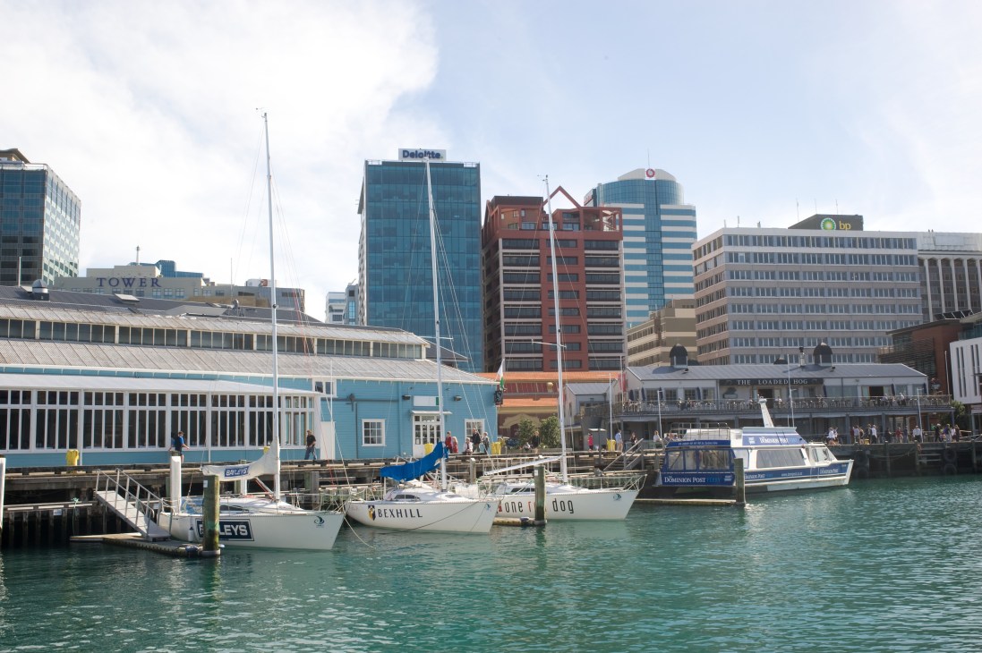 Wellington's central business district waterfront with sailboats, modern office towers, and historic buildings along the harbor.