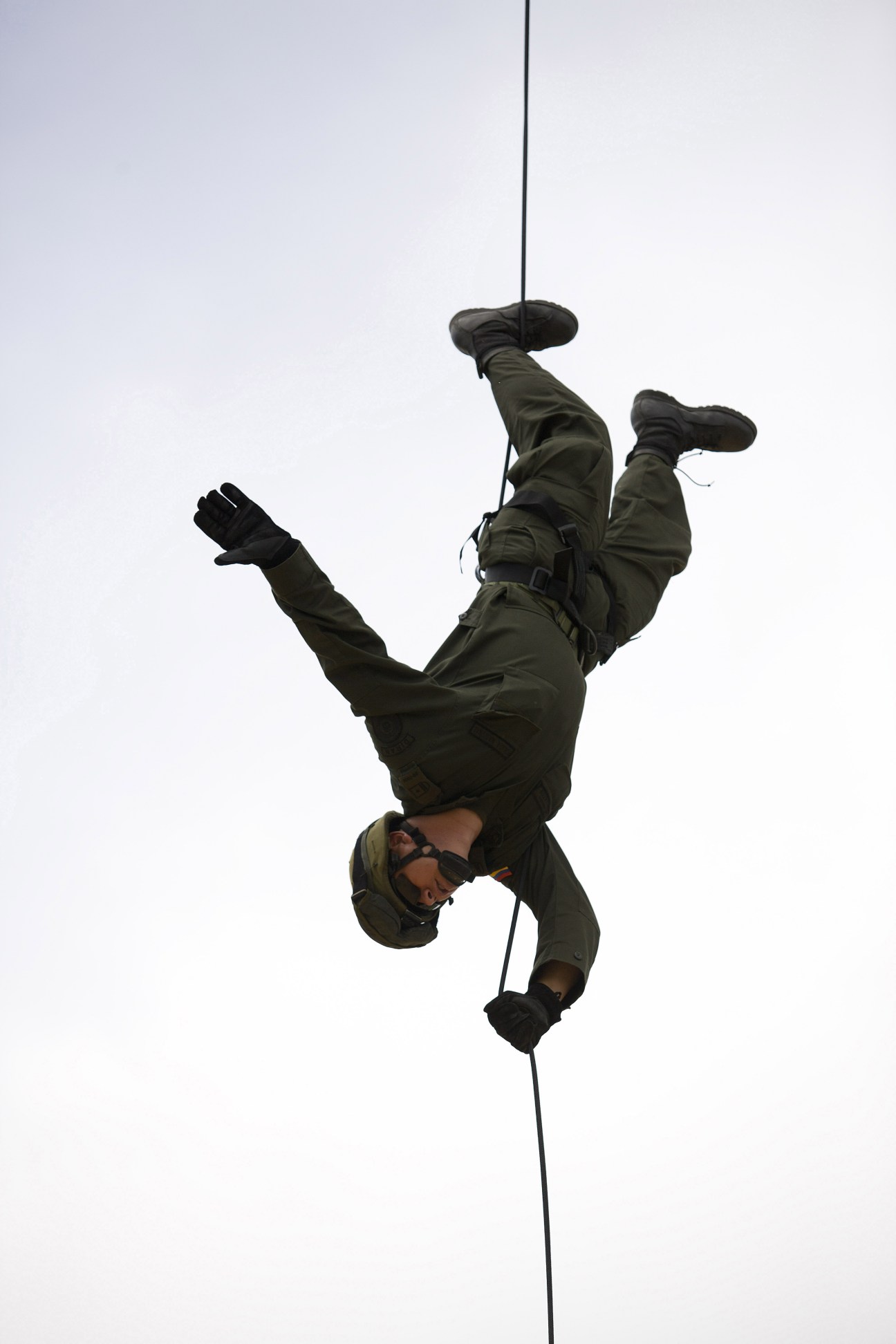 A police officer descends upside down on a rope during rappelling training.