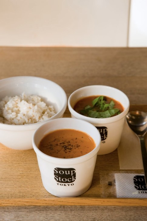 Two white ceramic bowls of soup with Soup Stock Tokyo branding on a wooden counter
