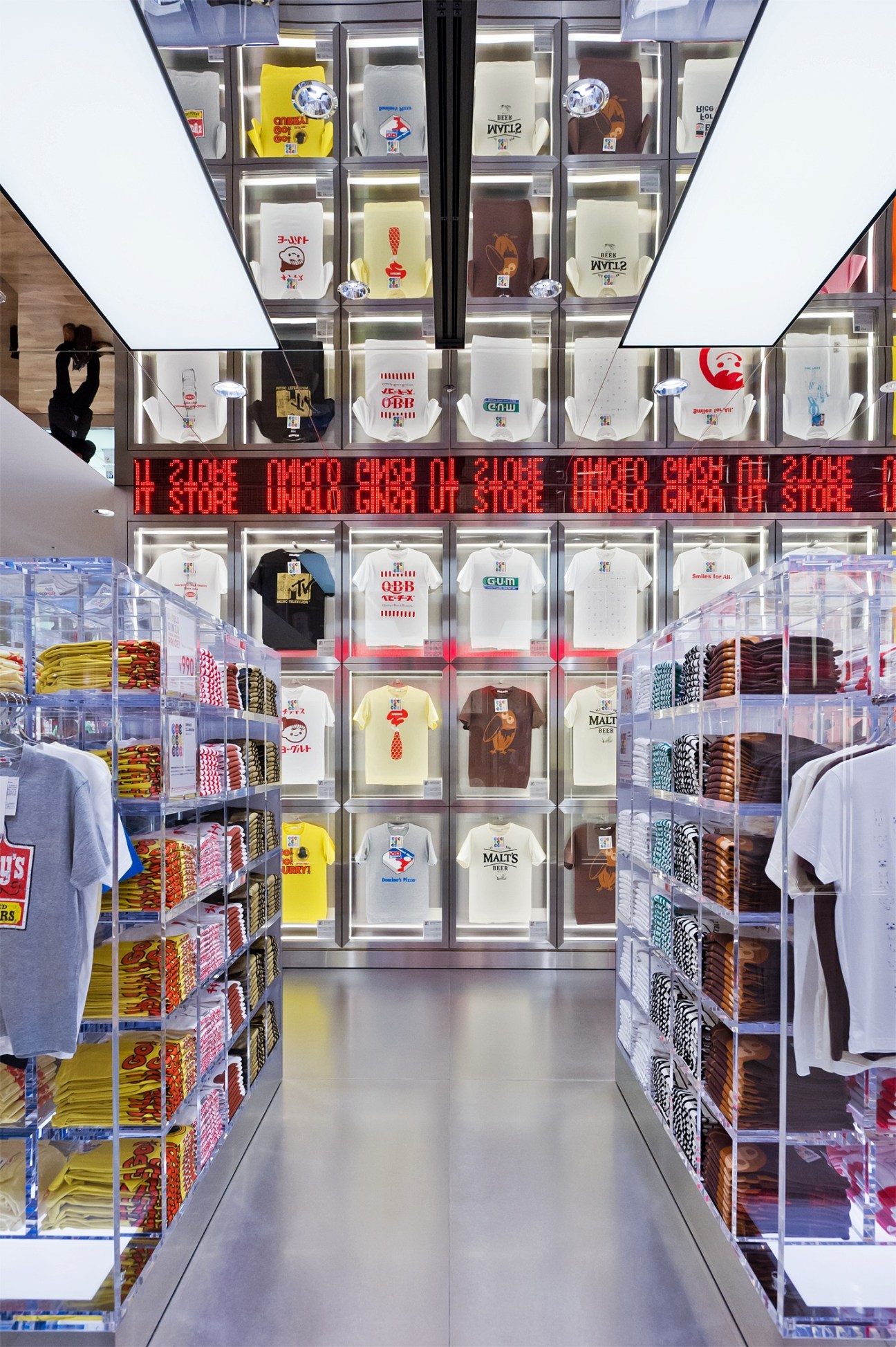 Uniqlo vending machine display with illuminated shelves stocked with colorful branded T-shirts and merchandise.