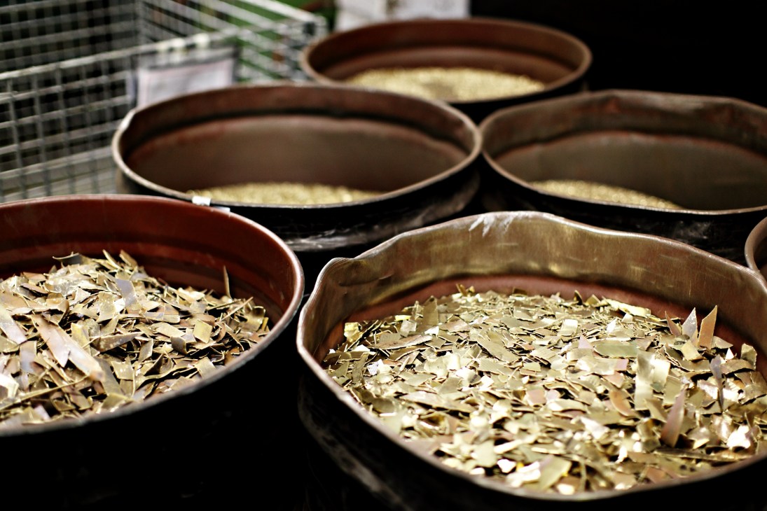 Multiple metal bins containing copper scraps and shavings at Zildjian cymbal factory.