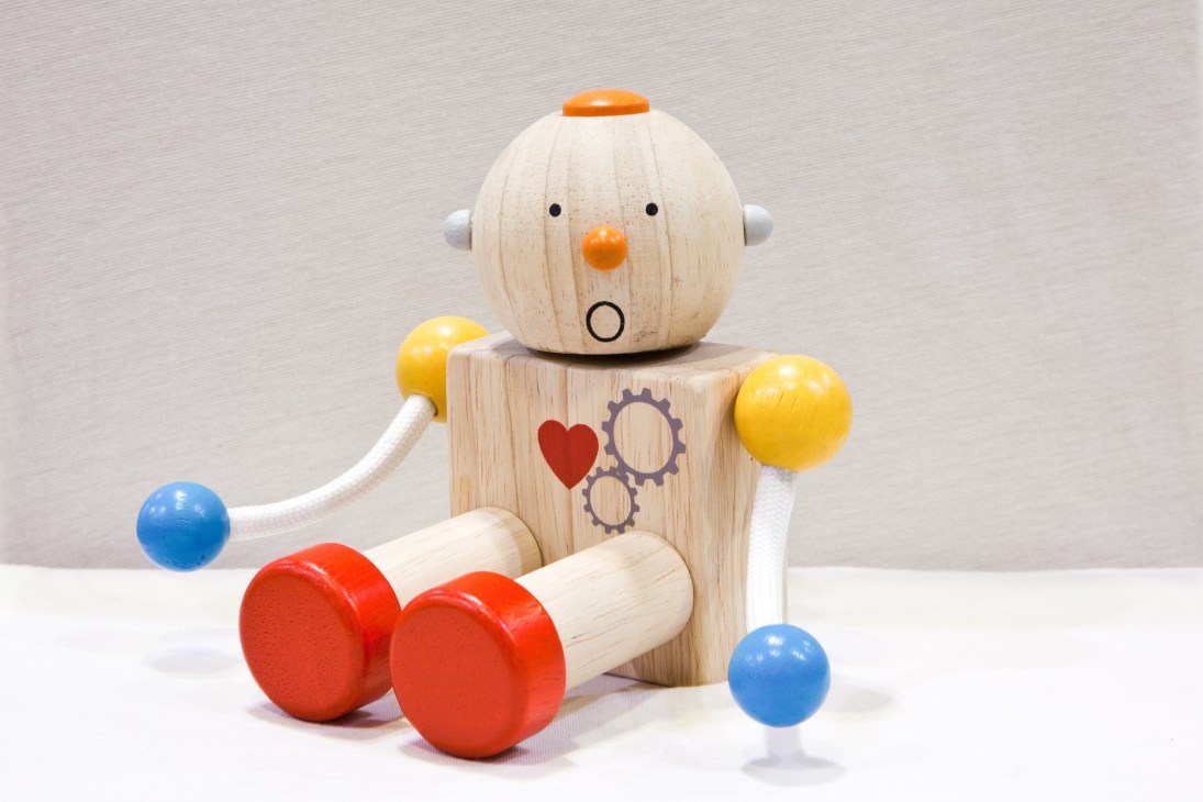 Wooden toy robot with colorful balls and accessories on white background.