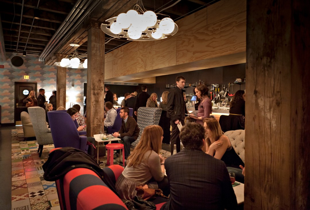 Interior of Marvel Bar in Minneapolis showing patrons at a cocktail event with colorful seating and modern lighting fixtures.