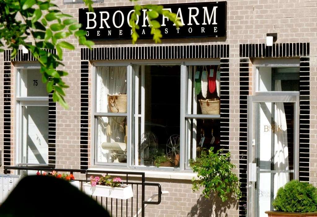 Brook Farm General Store storefront with black signage and large windows displaying products and a bicycle.