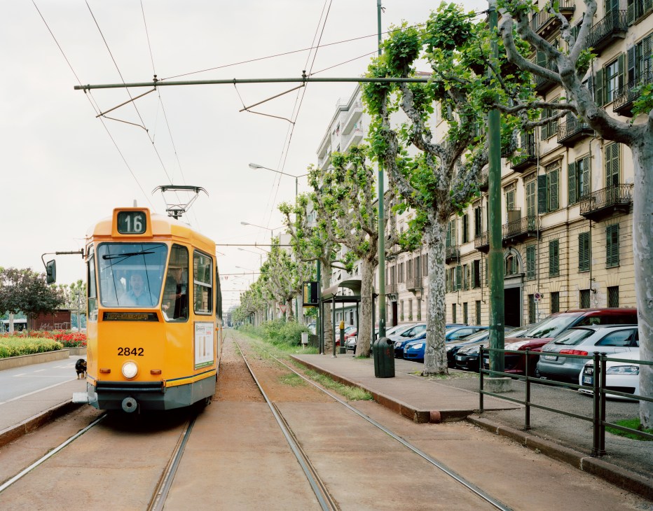 Orange tram number 16 traveling on tracks along Corso Cairoli in Turin, with historic buildings and tree-lined street.