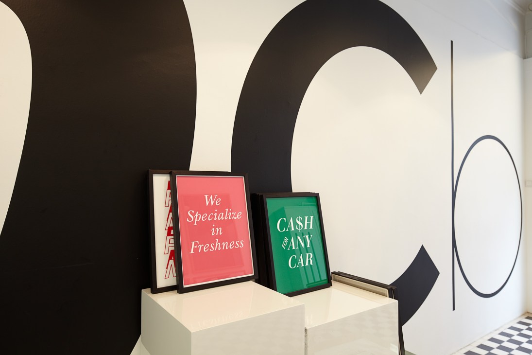 Font-themed prints displayed on pedestals in Playtype shop with large typographic wall decoration.