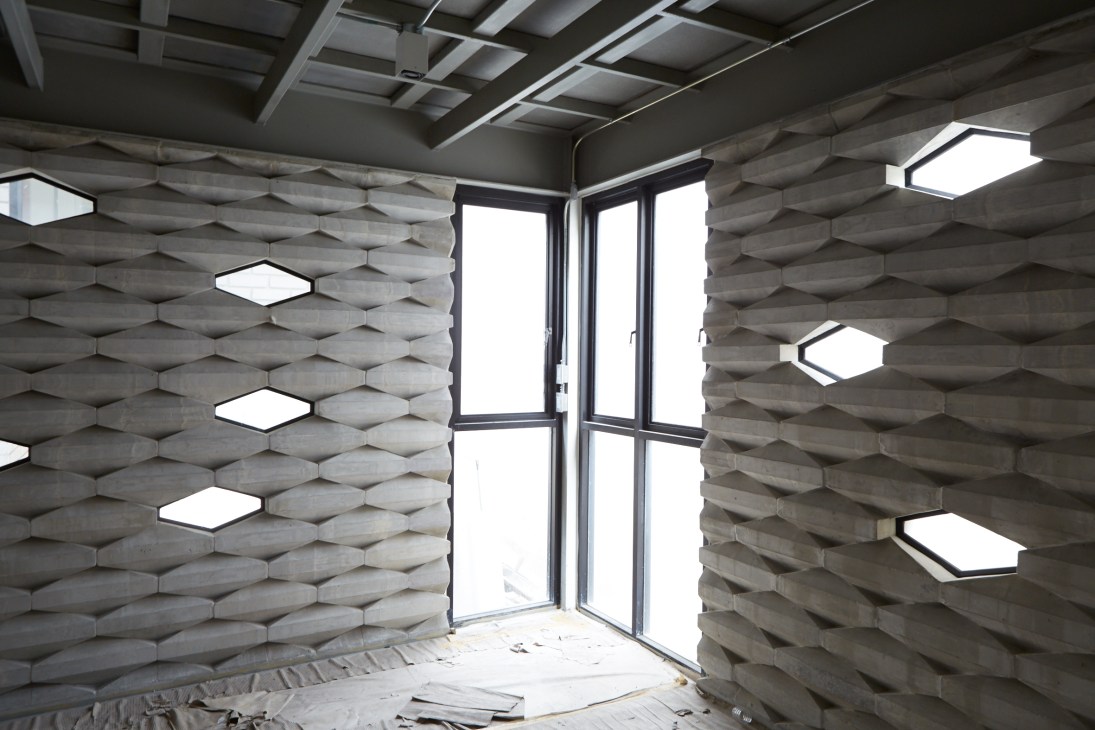 Interior space with textured brick walls, skylights, and glass doors opening to natural light.