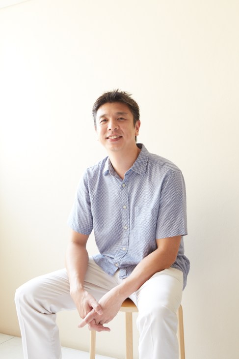 Portrait of Chat Architects director Chatpong Chuenrudeemol sitting on a stool against a cream background.