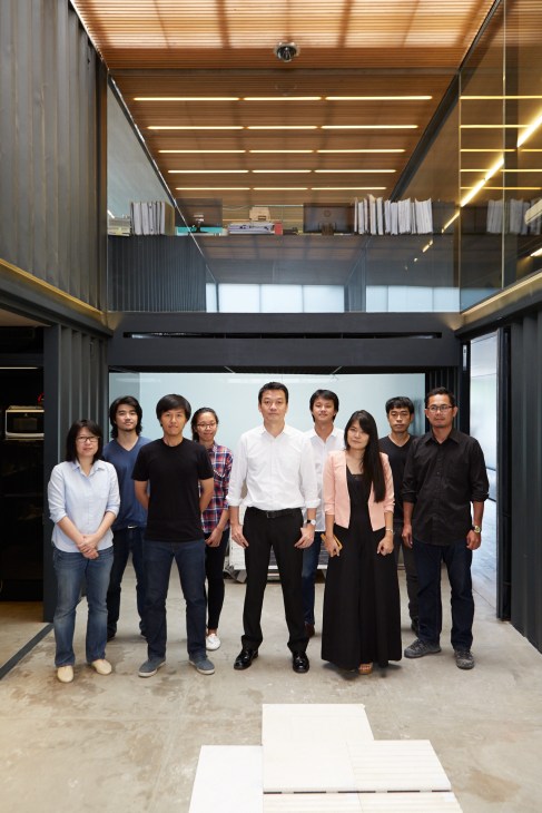 Boon Design founder Boonlert Hemvijitraphan stands with his team in their office made from shipping containers and metal screens.
