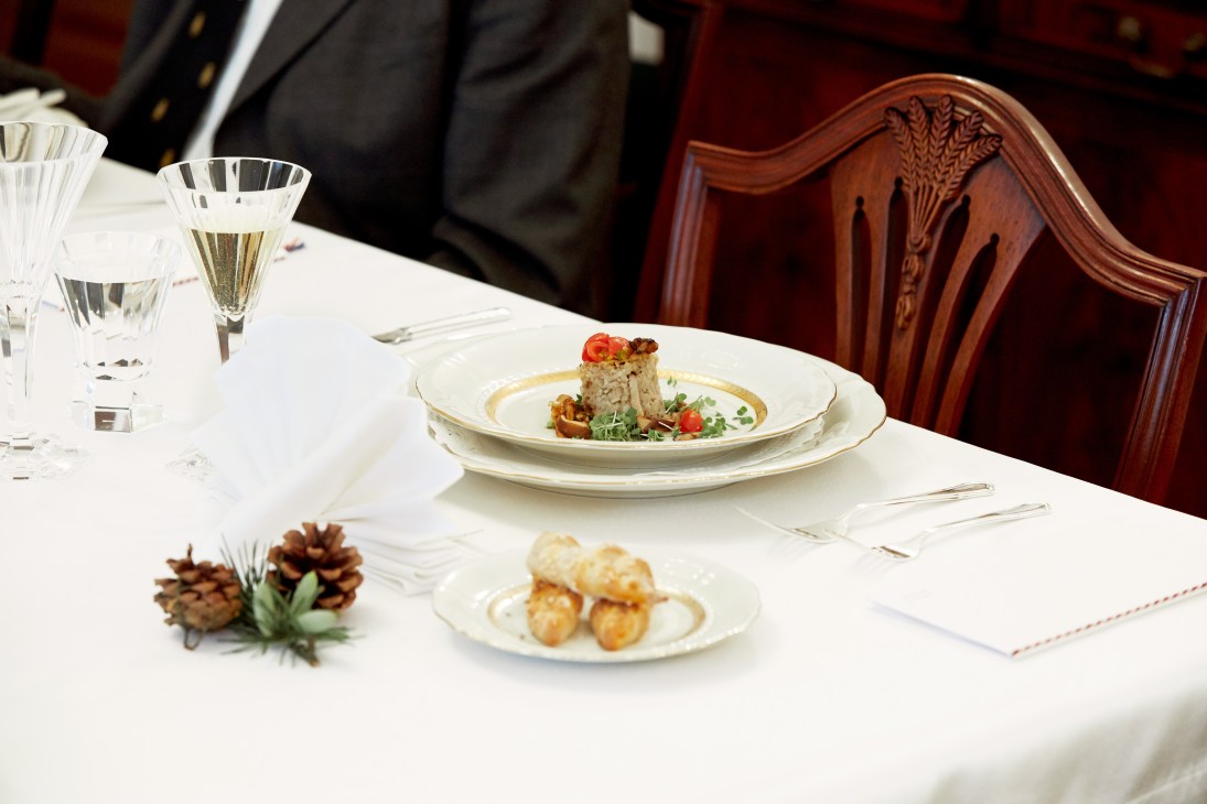 Elegant plated Czech dishes with creamy soup and fish schnitzel on white plates with wine glasses.