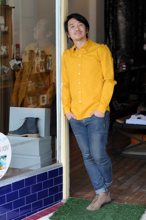 Johann Kim, owner of The Fox Hunt menswear store, stands in a yellow shirt outside his storefront.