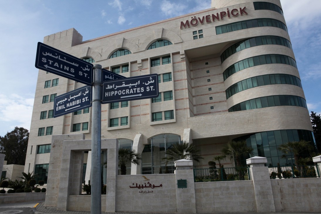 Street signs in front of the Mövenpick Hotel in Ramallah, showing bilingual Arabic and English signage.