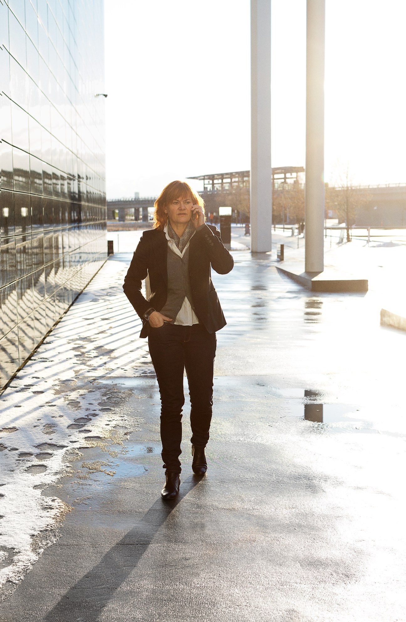 Piv Bernth, co-head of drama at Danmarks Radio, jogging through a modern courtyard with wet pavement and architectural columns.