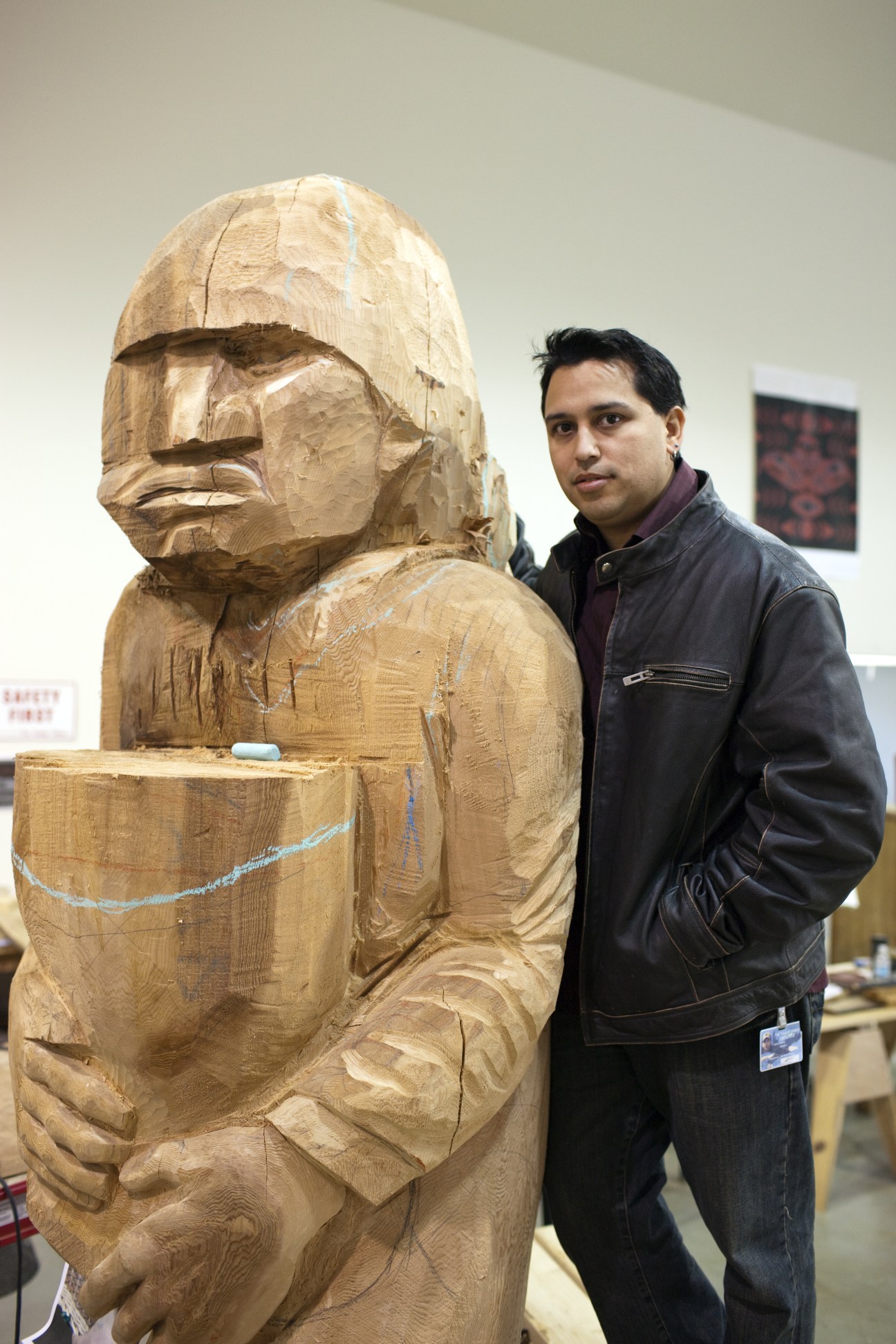 James Madison, a wood carver at Tulalip Tribal art centre, standing beside a large wooden totem carving.