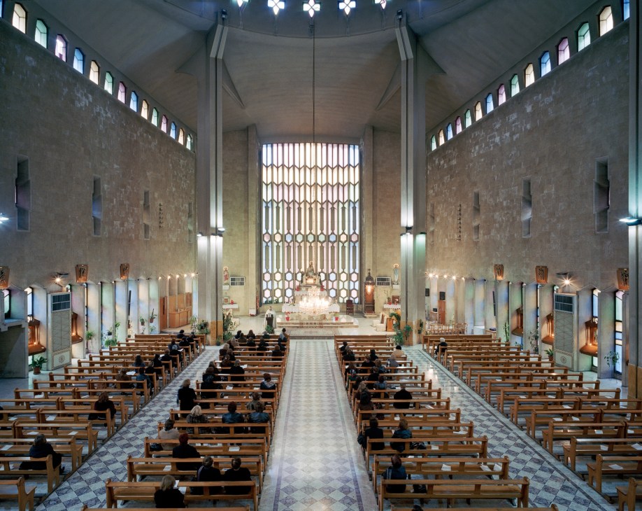 Interior of Mother Teresa Notre Dame de Dormition, a Catholic Syriac church in Aleppo with wooden pews and ornate altar.