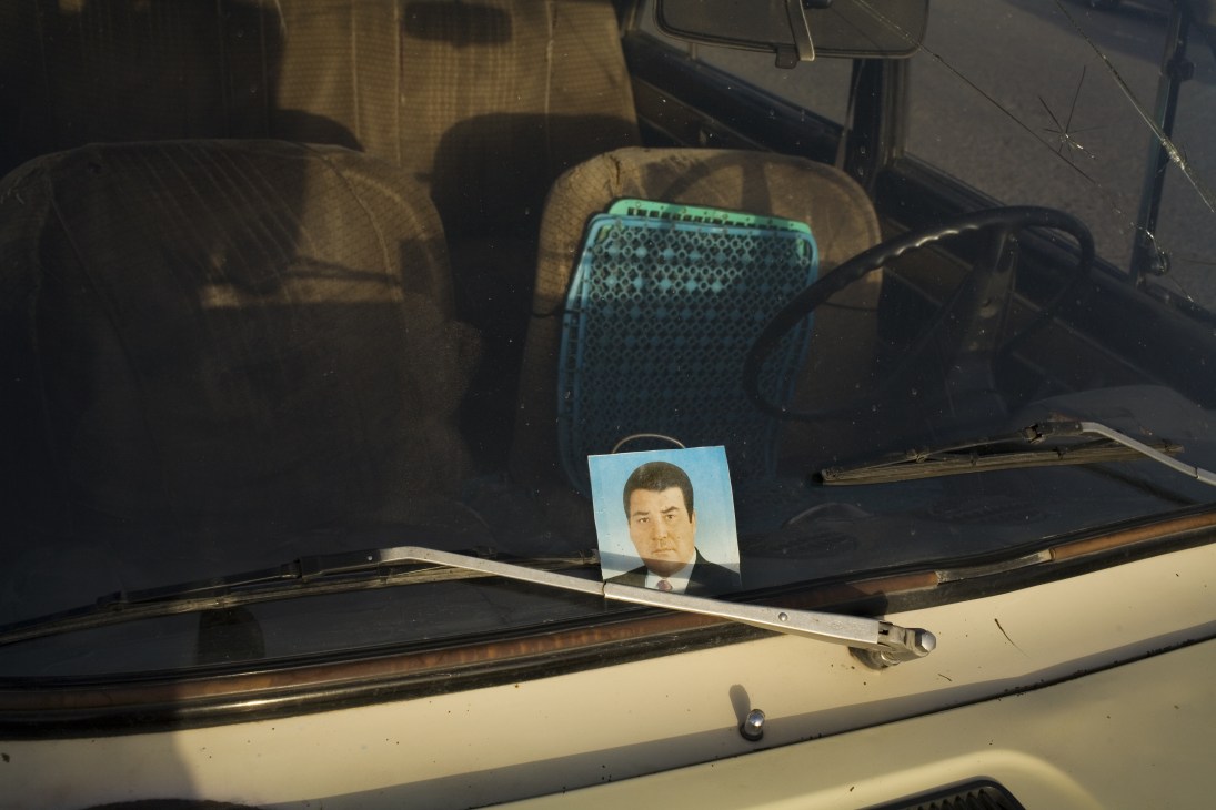 A portrait of President Berdymukhamedov displayed on a car dashboard.