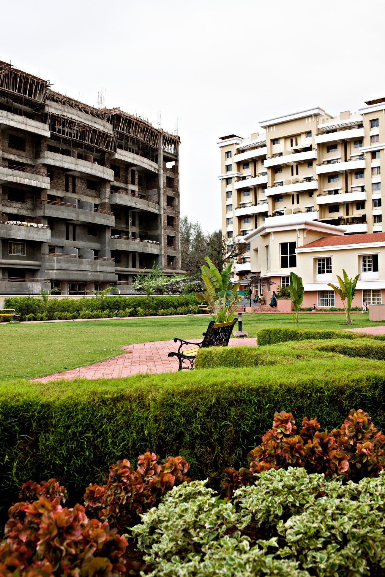 Luxury residential apartments under construction beside an unfinished concrete building in Pune.