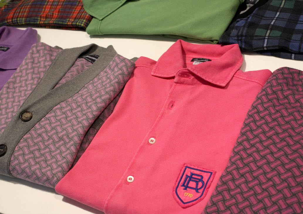Folded polo shirts and cardigan by Drumohr in pink, purple and patterned fabrics.