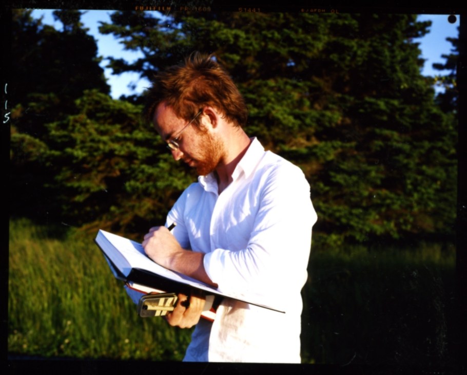 University of Calgary student Kristofer Kelly reviewing architectural plans outdoors with trees in background.