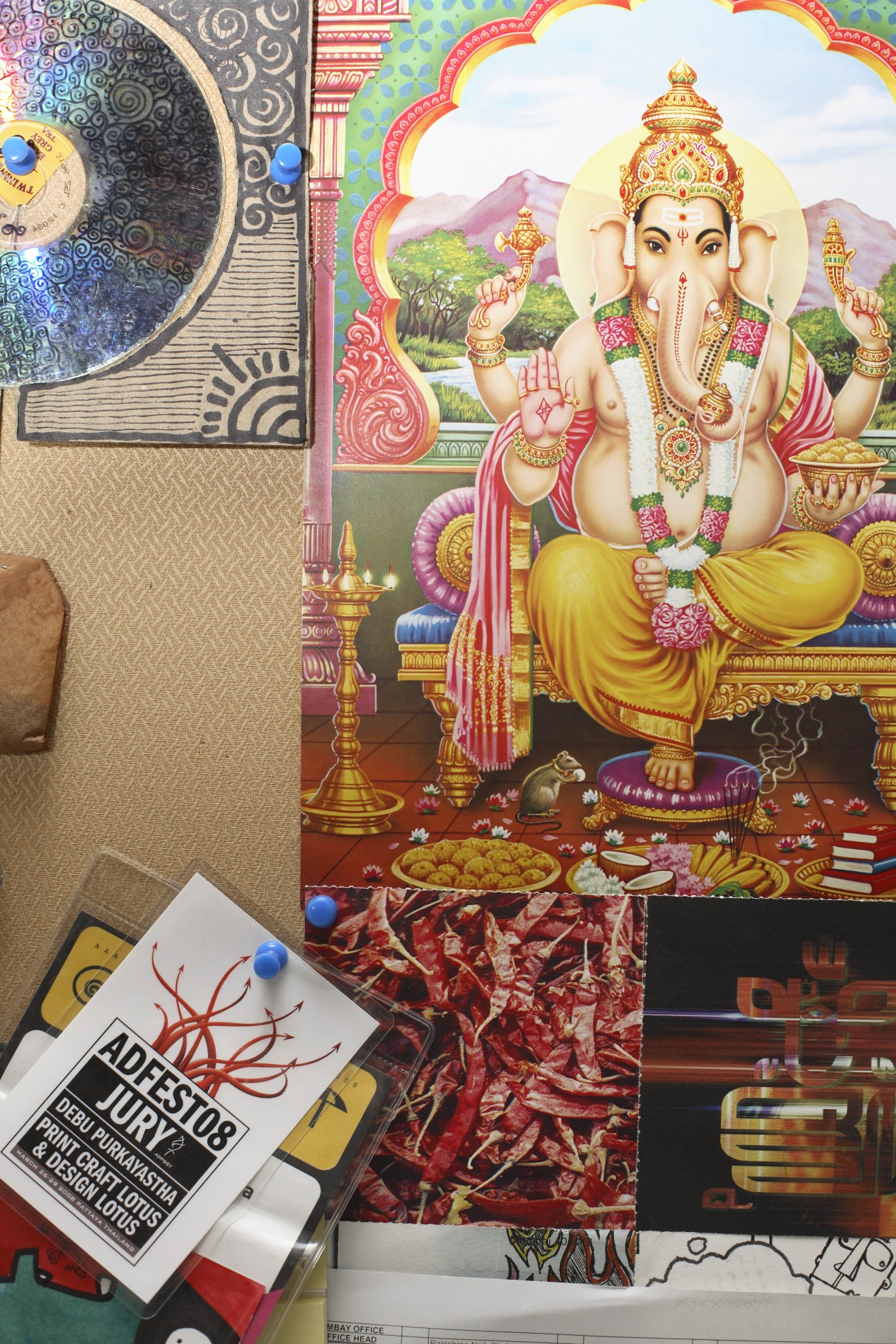 Hindu deity Ganesh poster alongside event badges in a modern Mumbai advertising agency office.