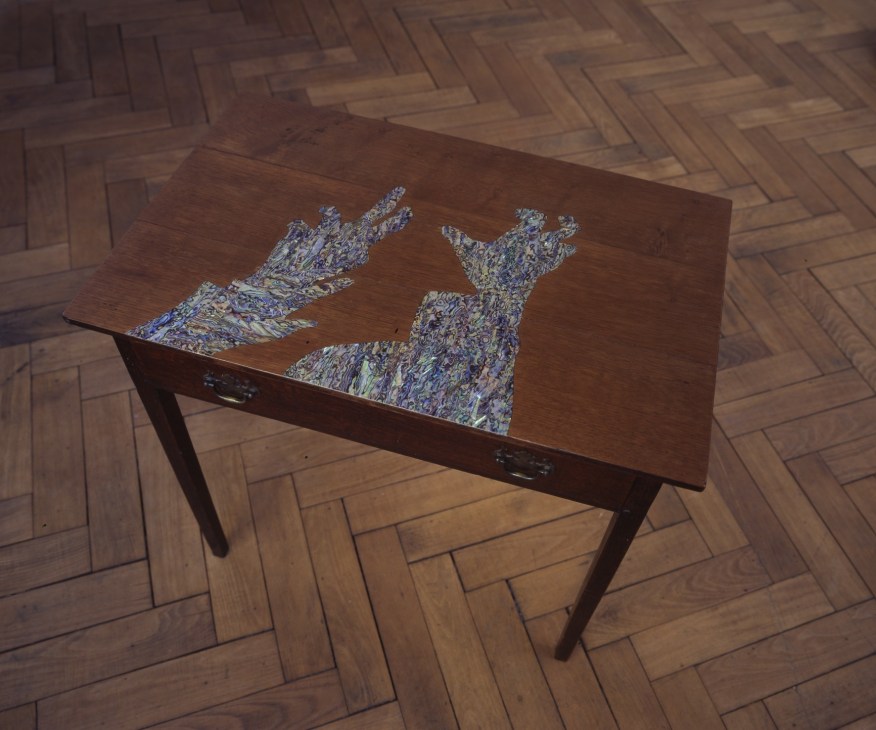 Lucy Skaer artwork featuring abstract textured forms displayed on a wooden table with herringbone flooring.