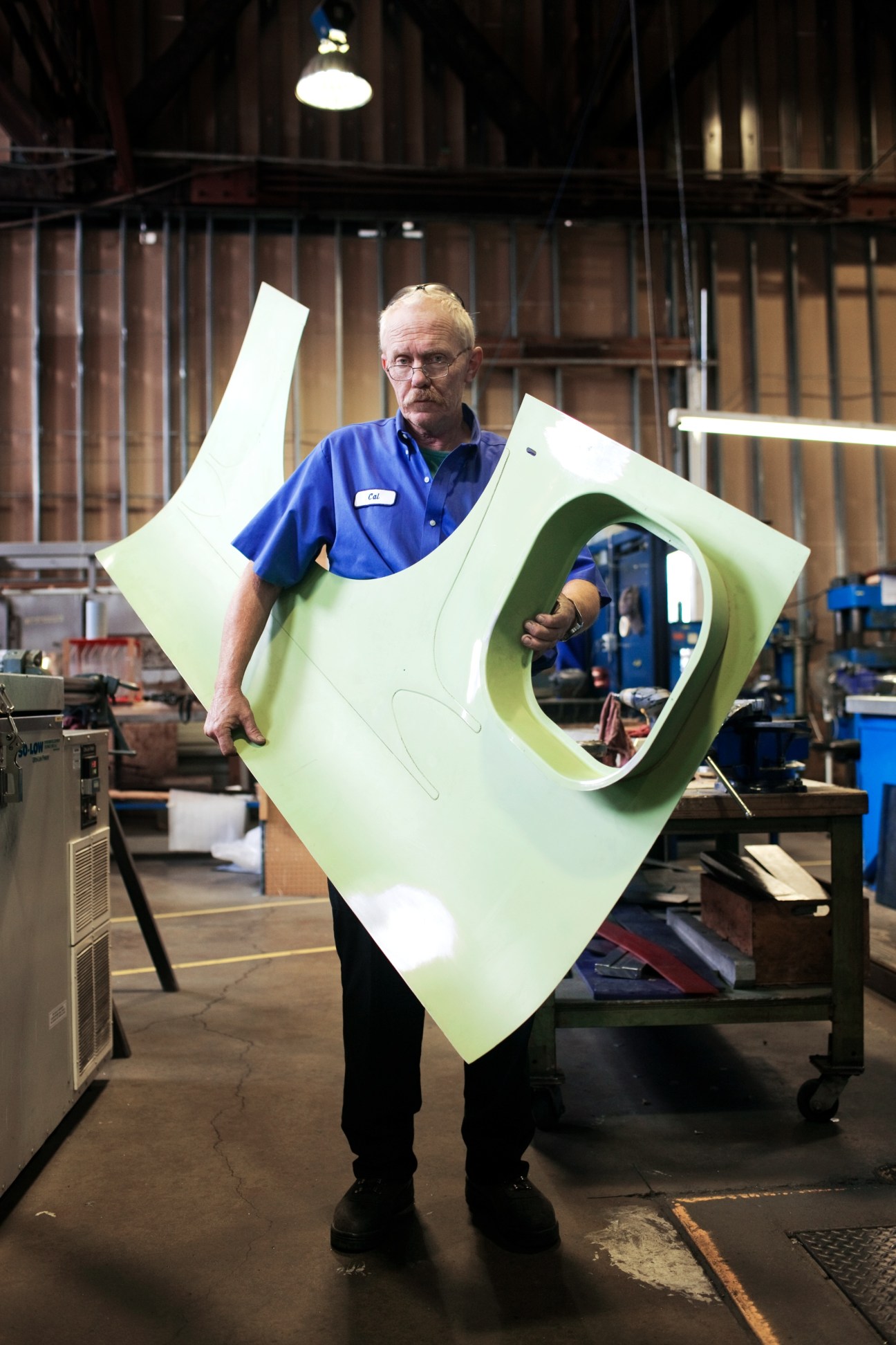 Viking Air employee Cal Pilling holds a large pale green aircraft component in the factory.