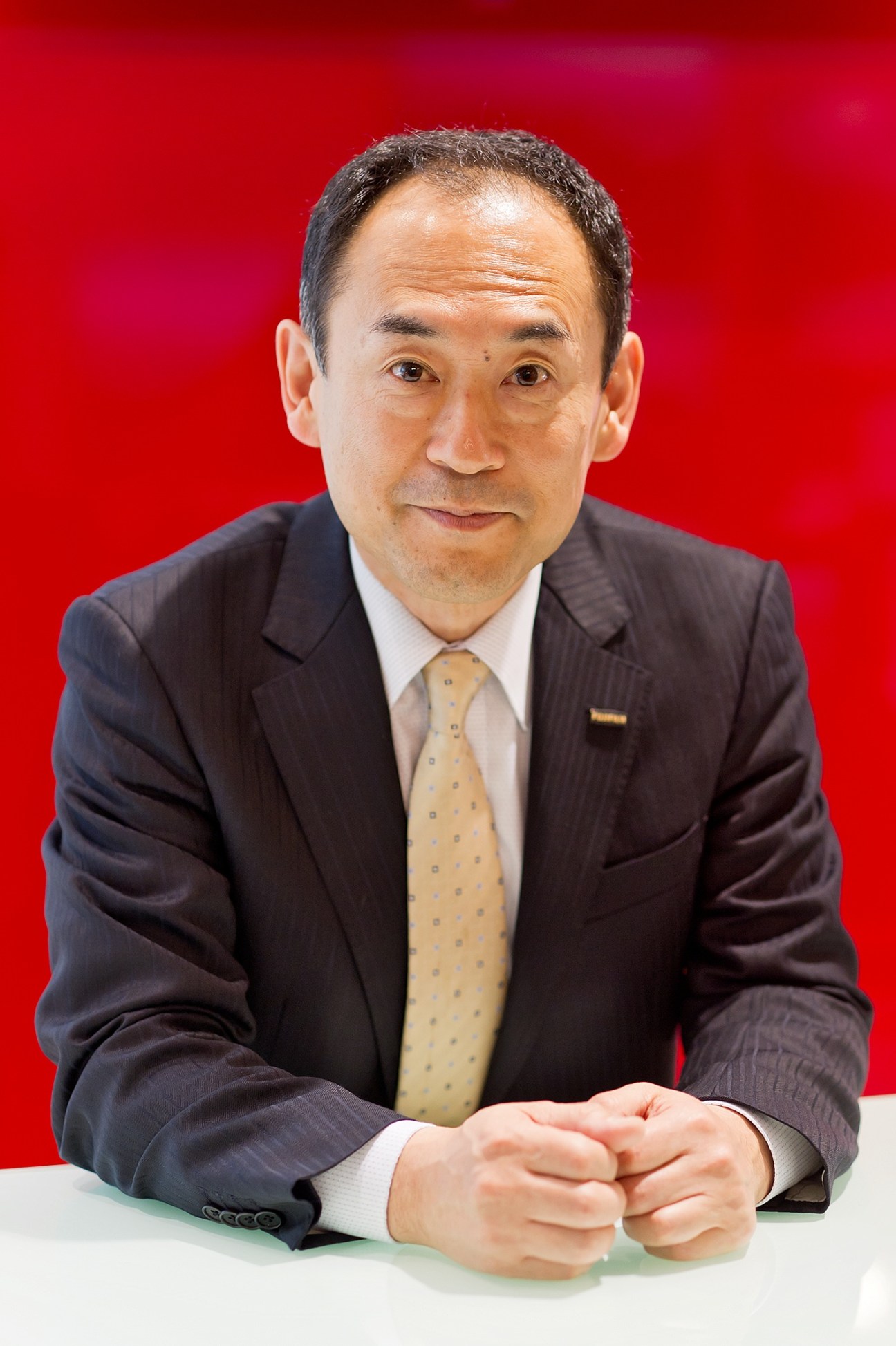 Yojiro Yamashita, general manager of Fujifilm's life science products division, poses against a red background.