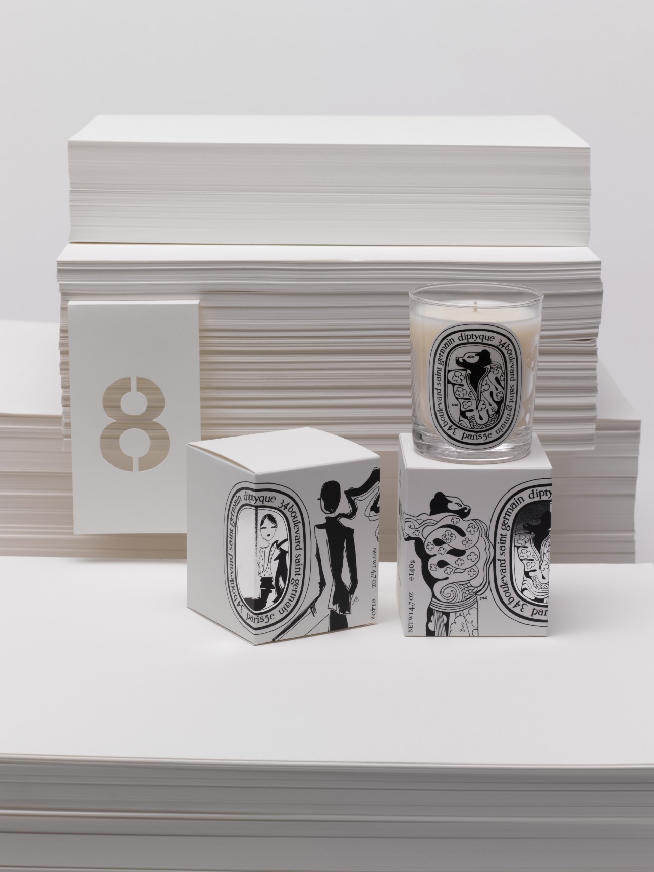 Diptyque candles in black and white packaging with illustrated Belle et Bête designs displayed with striped boxes.