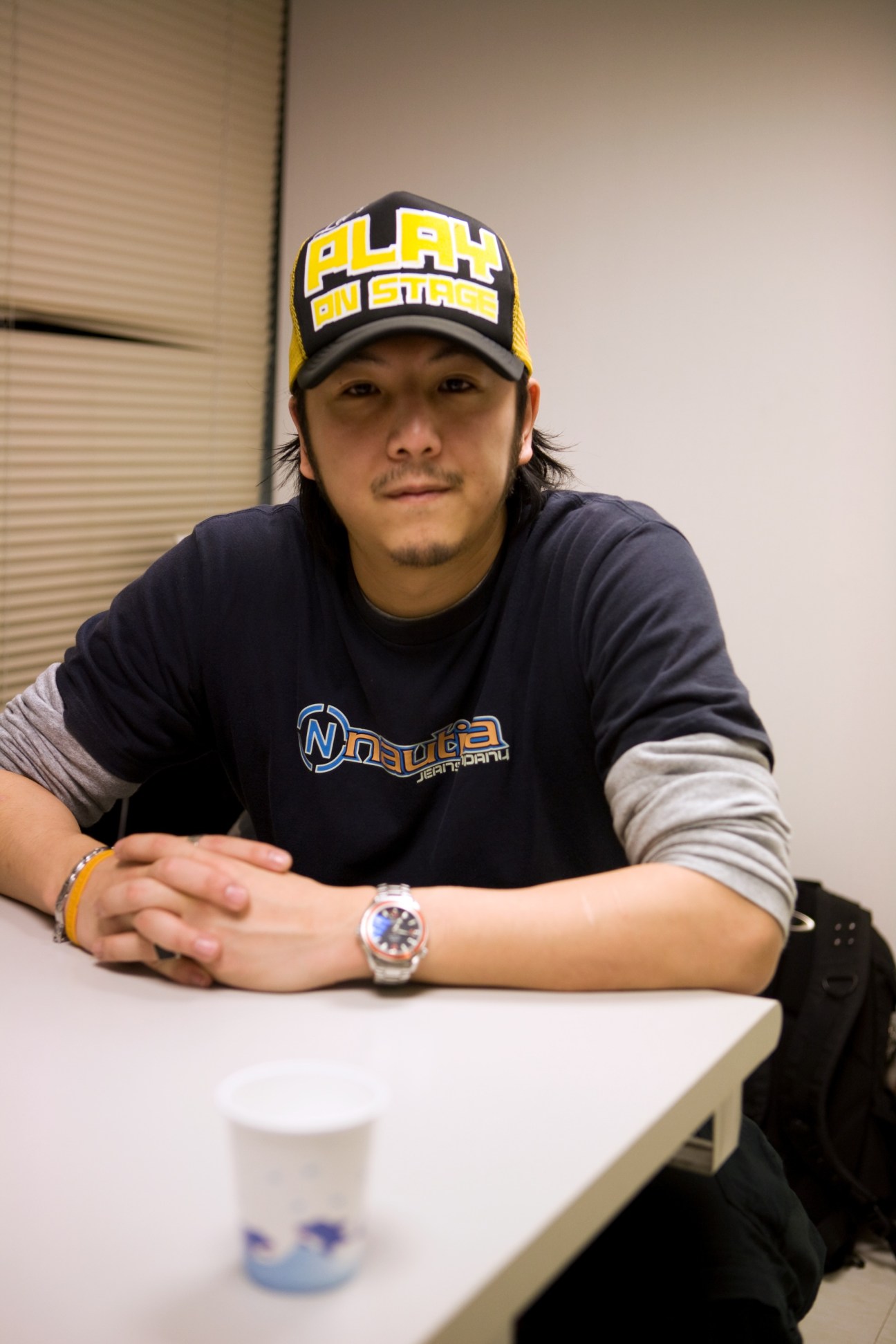 Daniel Bi, manager and A&R at Universal Music, wearing a yellow and black baseball cap and dark t-shirt, seated at a table.