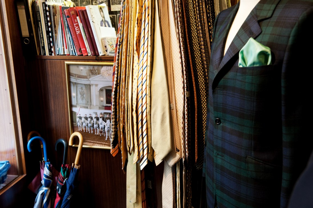 Interior of Netoussek bespoke tailoring shop displaying fabrics, suit jackets, umbrellas and books.