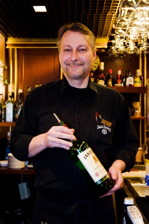 Barman Peik Kanervavuori holds a bottle of Jameson Irish whiskey behind the bar on M/S Gabriella.