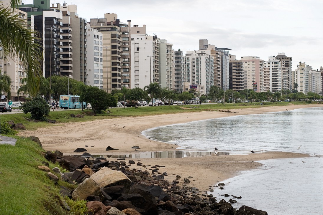 Beach and waterfront promenade with high-rise residential apartments lining the shore in Florianópolis.