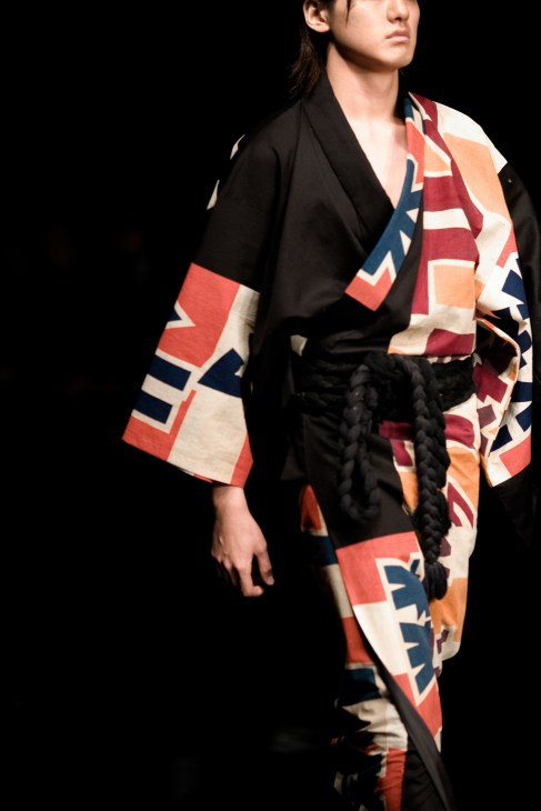 Model wearing black and patterned cotton yukata with geometric design and braided obi belt