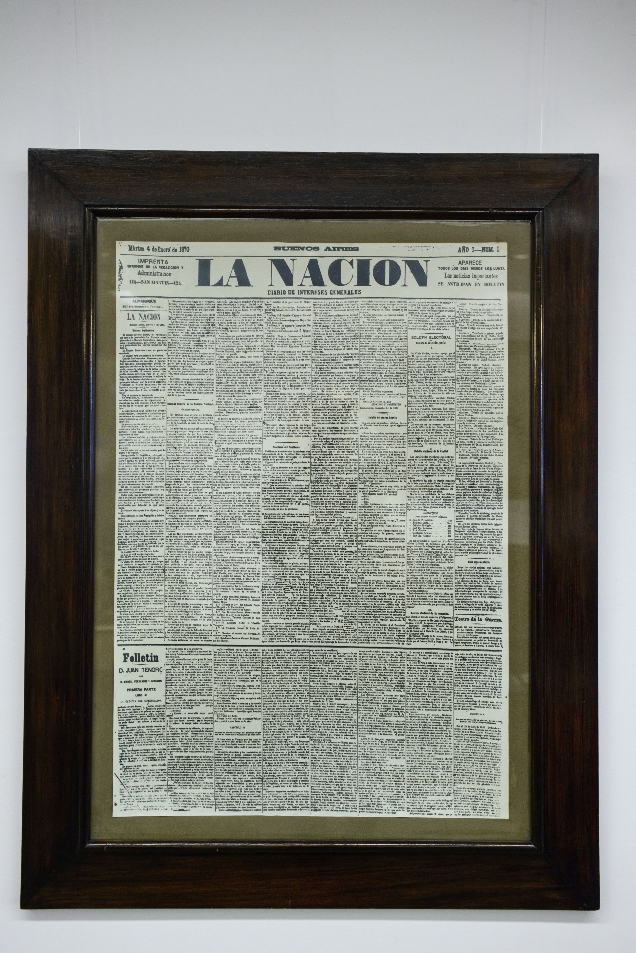 Framed historical front page of La Nación newspaper from 1870, displaying dense columns of text with the masthead prominently featured.