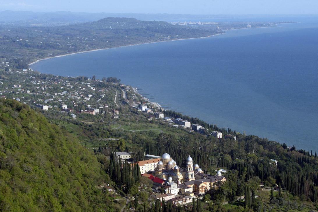Aerial view of the Black Sea coast near Sukhumi with a Orthodox church and coastal settlements nestled among green hills.