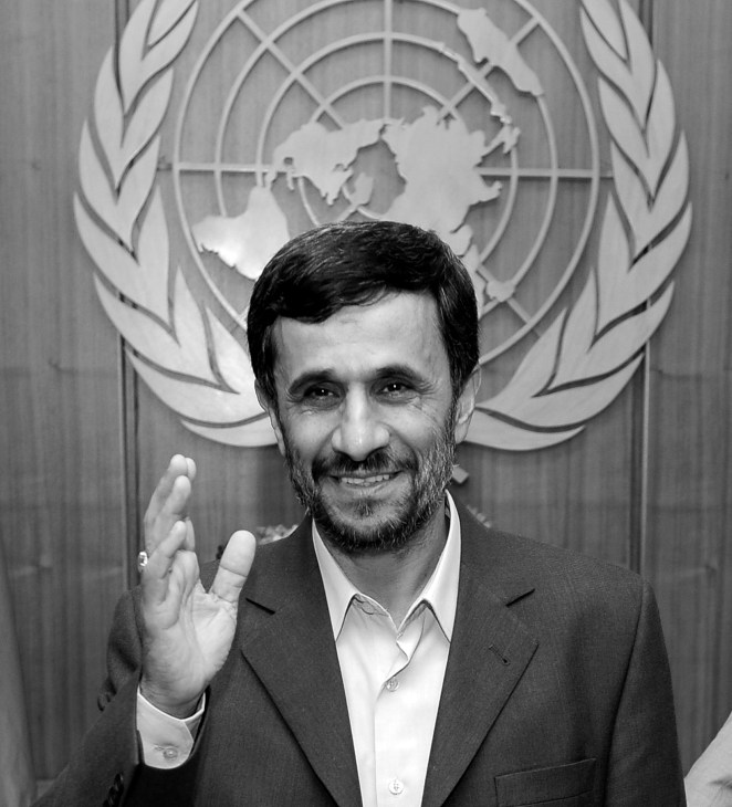 Black and white portrait of Iranian president Mahmoud Ahmadinejad waving in front of United Nations logo.